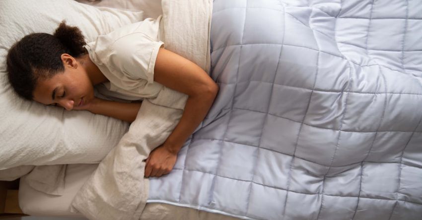 Sleep Quality - A woman sleeping in a bed with a quilt