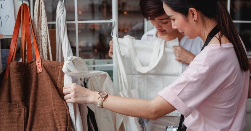 Sustainable Fashion - Trendy young Asian women choosing cotton bags in fashion boutique