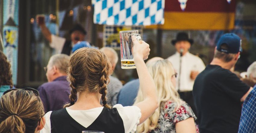 Oktoberfest - Woman Standing in a Crowd Holding Up Beer Glass